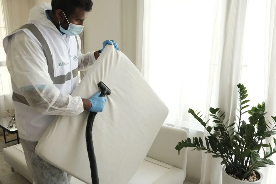 A couple wrapping furniture in a bright apartment, preparing to move.